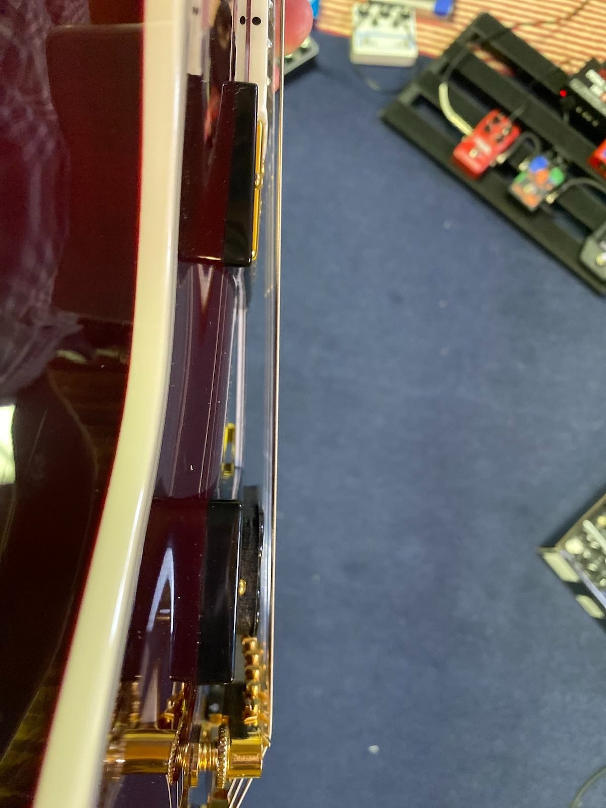There's not much distance between the bridge pickup and the strings, which is part of the reason it's so hot, even on my Katana's clean channel. You could easily settle this down by physically lowering the pickup. In this picture you can see more space above the neck humbucker. There's not much distance between the bridge pickup and the strings, which is part of the reason it's so hot, even on my Katana's clean channel. You could easily settle this down by physically lowering the pickup. In this picture you can see more space above the neck humbucker.